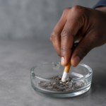 Close-up of a person stubbing out a cigarette, illustrating smoking and gum disease risk.