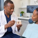 Dentist examining a dental implant model with a patient as she explains to her about dental implants in a Nairobi dental clinic.